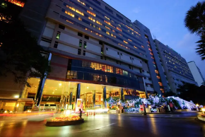 Bumrungrad International Hospital entrance and illuminated building at night.