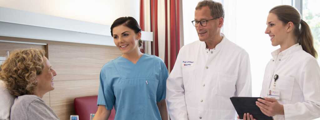 Clinical staff speaking with a patient on the HDZ NRW cardiac surgery department page